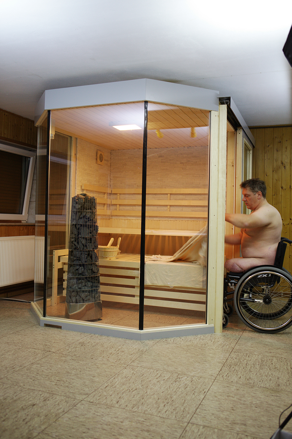 Barrierefreie Heimsauna mit Schiebetür während des Einstiegs vom Rollstuhl aus